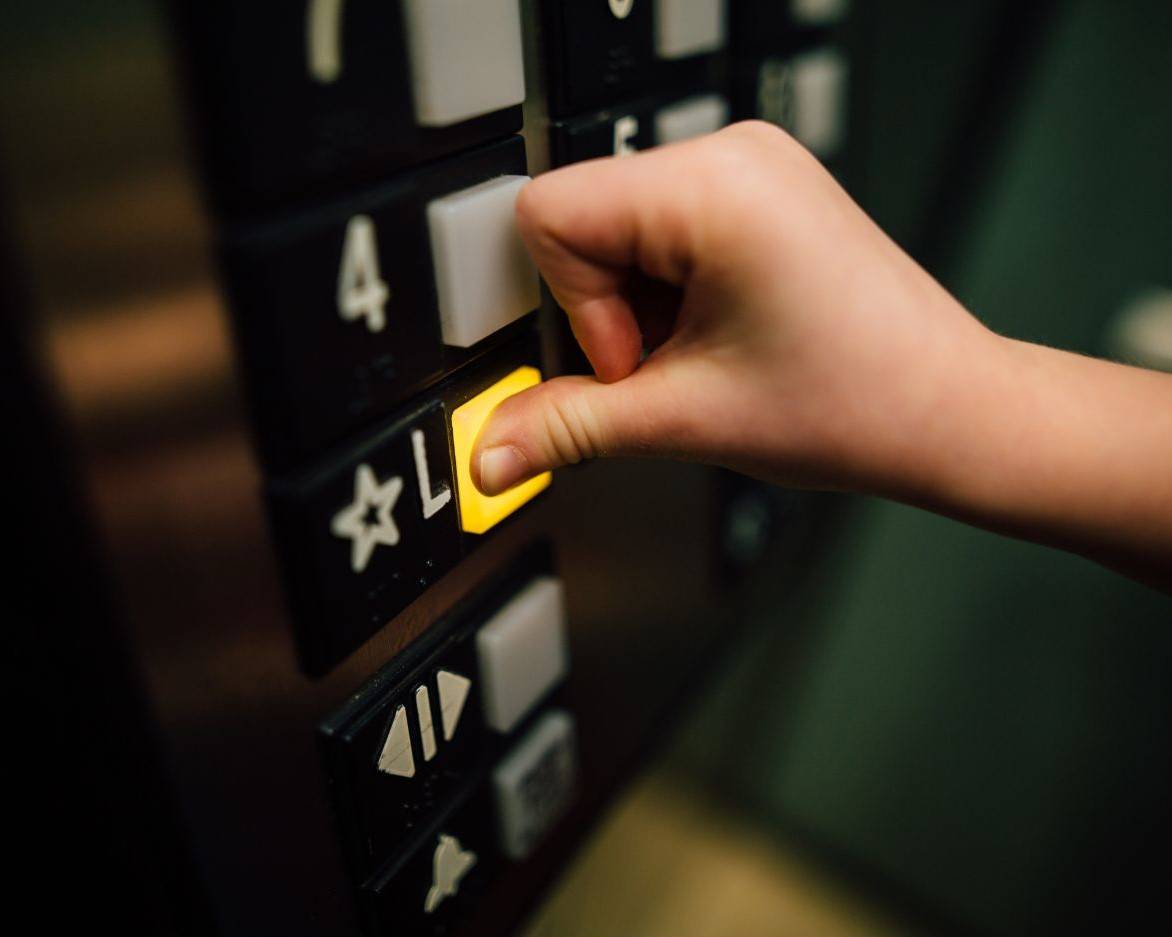 Close up of a hand pressing a lift button.