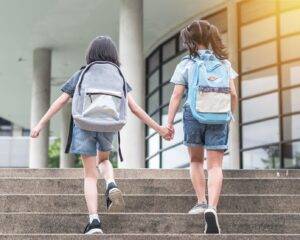 Two children holding hands walking up stairs.